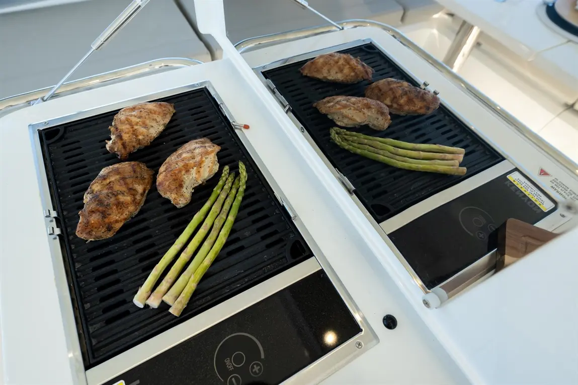 Grilled chicken breasts and asparagus spears on a modern stove's grill, showcasing delicious meal preparation.